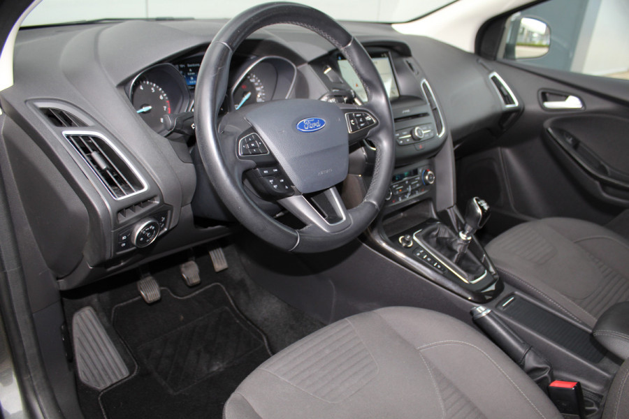 Ford Focus 1.0-125pk Titanium. Erg nette en luxe Ford Focus. Stoel-, stuur- en voorraamverw., autm. airco dual, navigatie, metallic lak, telefoonvoorb., camera, pdc v+a, dodehoek assist, AllSeason banden rondom, trekhaak, LM wielen etc.
