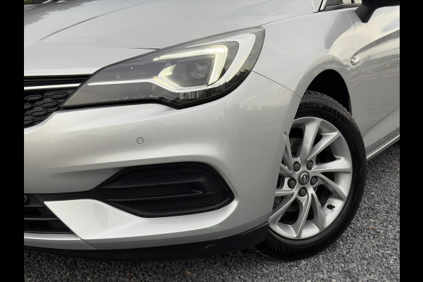 Opel Astra Sports Tourer 1.2 Elegance ✓110pk✓Camera✓Carplay✓Navi✓Halfleder✓Keyless✓Trekhaak✓Pdc V+A✓Clima✓Cruise✓Elekt Stoel✓Recent beurt gehad✓Dodehoeksensor✓Rijstrooksensor✓Lm velgen✓N.A.P✓Apk tot 11-2027