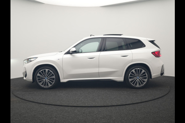 BMW iX1 xDrive30 M Sport 313pk Dealer O.H. | Trekhaak Af Fabriek | Panodak | 360 Camera | Head Up | Lederen Sportstoelen Memory & Verwarmd | Stuur Verwarmd | Keyless | BLIS | Sfeerverlichting | Apple Carplay | Navigatie | DAB | 20"L.M