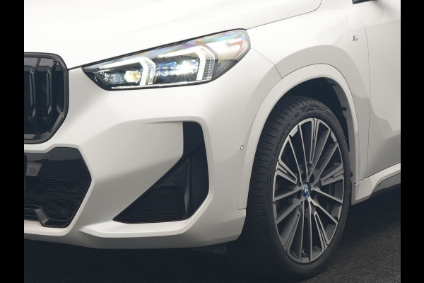 BMW iX1 xDrive30 M Sport 313pk Dealer O.H. | Trekhaak Af Fabriek | Panodak | 360 Camera | Head Up | Lederen Sportstoelen Memory & Verwarmd | Stuur Verwarmd | Keyless | BLIS | Sfeerverlichting | Apple Carplay | Navigatie | DAB | 20"L.M