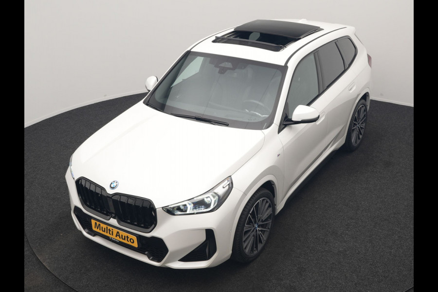 BMW iX1 xDrive30 M Sport 313pk Dealer O.H. | Trekhaak Af Fabriek | Panodak | 360 Camera | Head Up | Lederen Sportstoelen Memory & Verwarmd | Stuur Verwarmd | Keyless | BLIS | Sfeerverlichting | Apple Carplay | Navigatie | DAB | 20"L.M